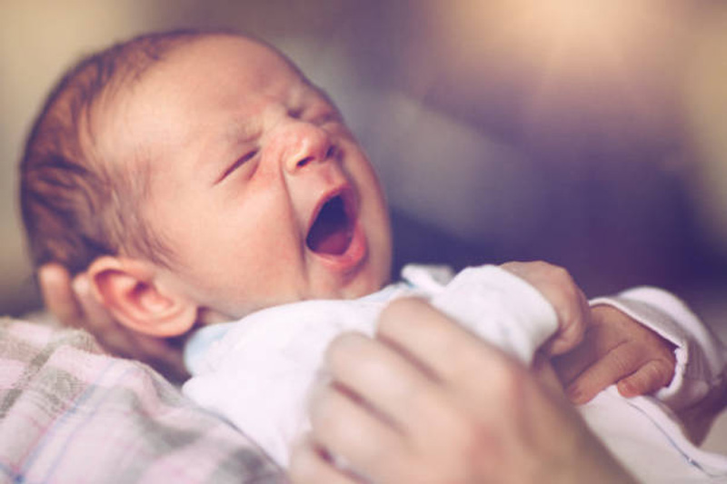 Sleepy newborn baby boy yawning